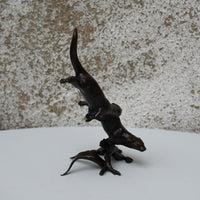 solid bronze sculpture of two otters swimming