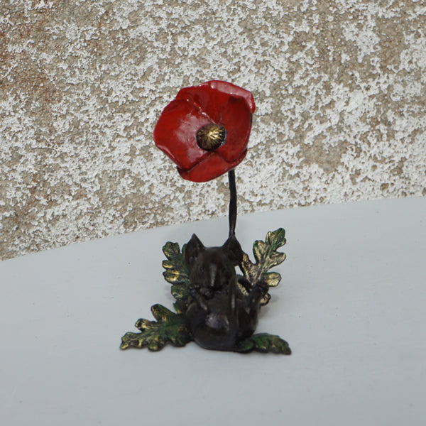 Small red flower and green plant on a textured surface with a white background