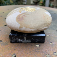 Decorative stone with gold accent on a black base outdoors