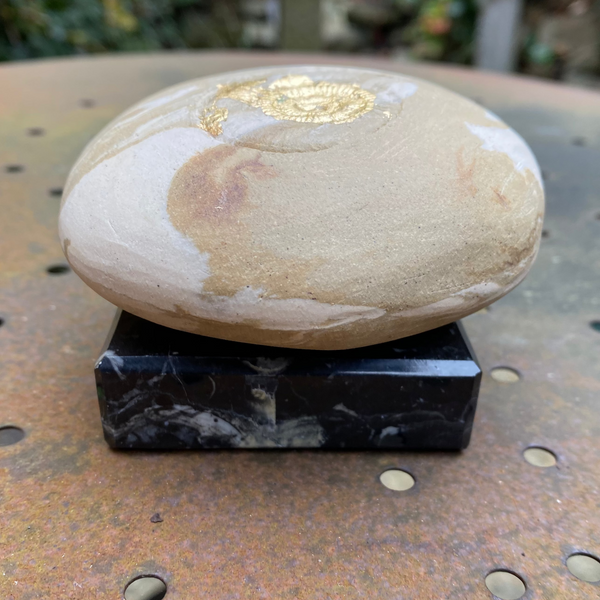 Decorative stone with gold accent on a black base outdoors
