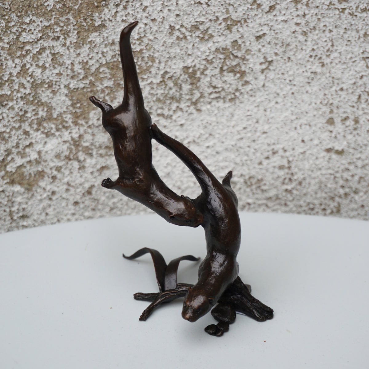 solid bronze sculpture of two otters swimming